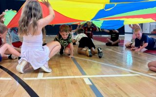Kids playing in a gym with parachute