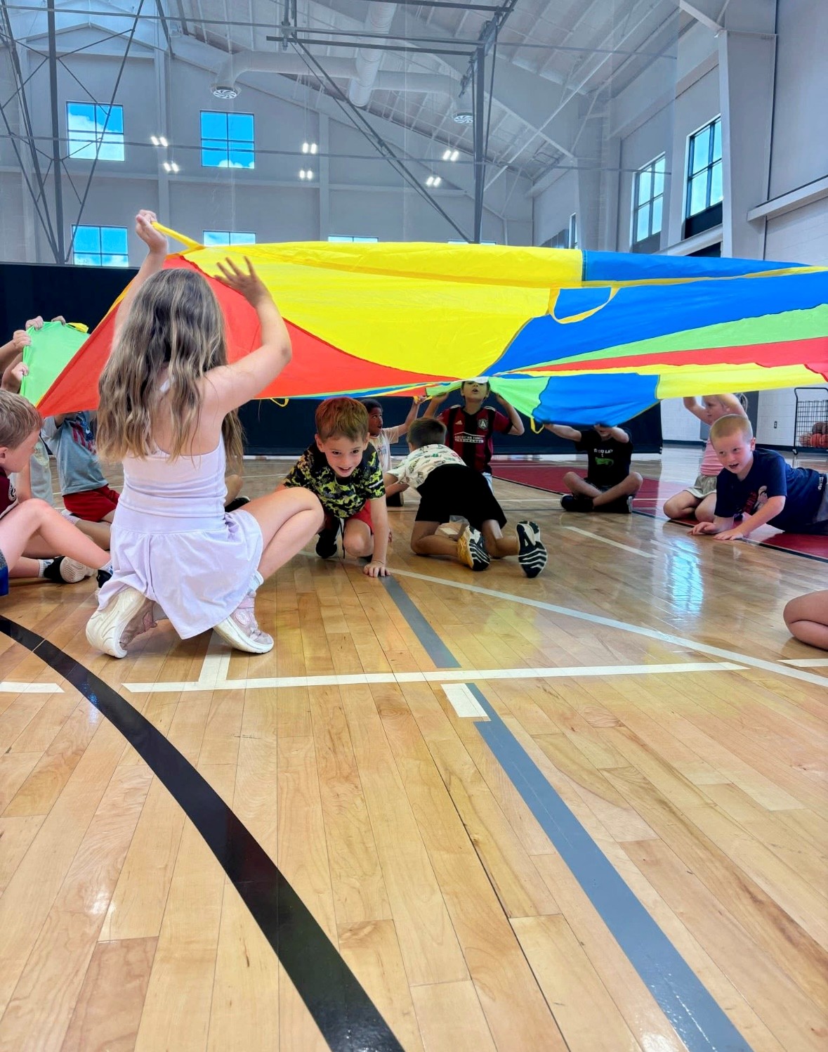 Kids playing in a gym with parachute