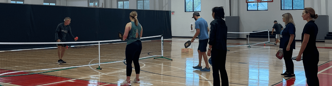 Class of 3 adults learning pickleball inside a gym