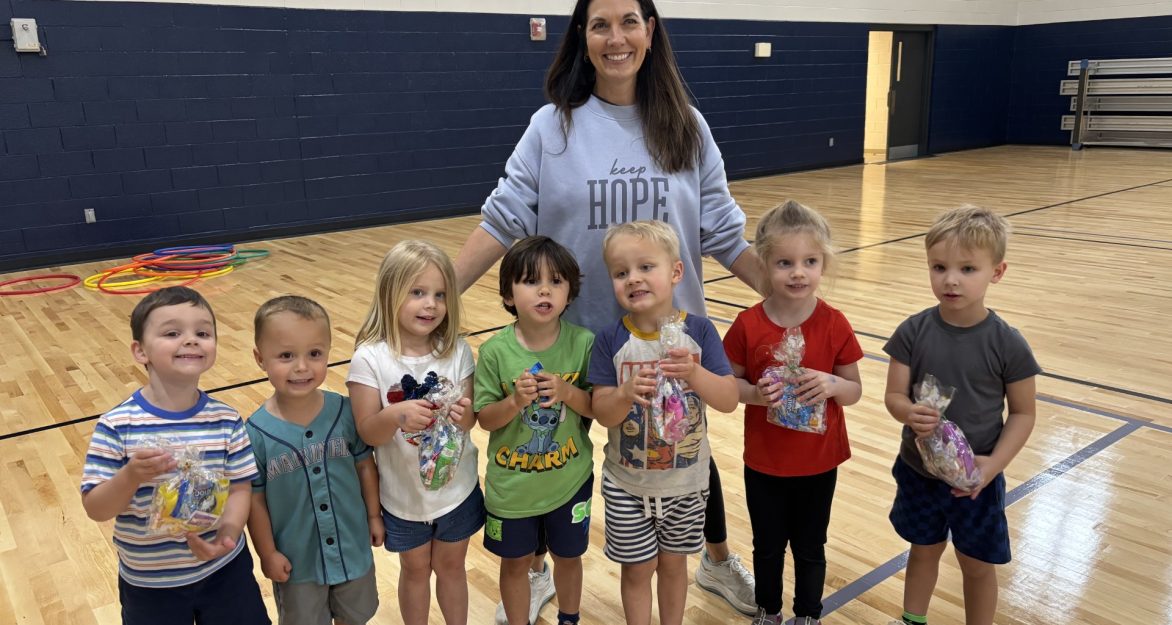 Little kids in a line with their teacher smiling