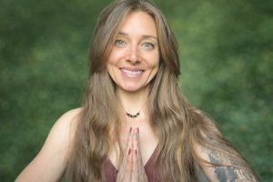 Brunette woman holds her palms pressed together in a meditation class